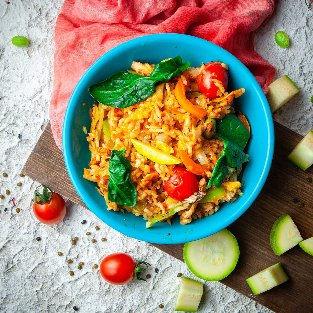 delicious meal in a blue plate on a wood, red cloth and white textured background. top view.